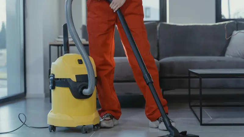 Cleaner vacuuming a living room floor